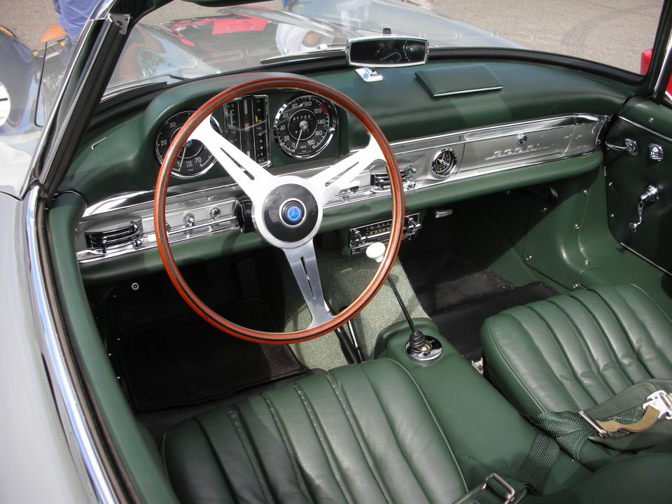 Green-leather interior of a Mercedes 300SL roadster with wood wheel
