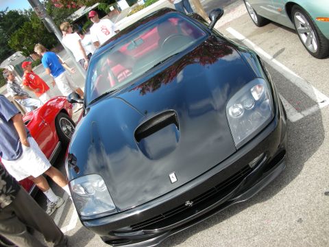 1998 Ford Crown Victoria - black Ferrari with a red leather interior parked at an outdoor car show, viewed from above the front bumper bearing the prancing-horse badg…