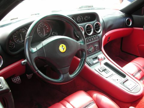 1998 Ford Crown Victoria - sports-car cockpit with a black Ferrari-badged steering wheel, gauge cluster, gated metal shifter and bright red leather seats.