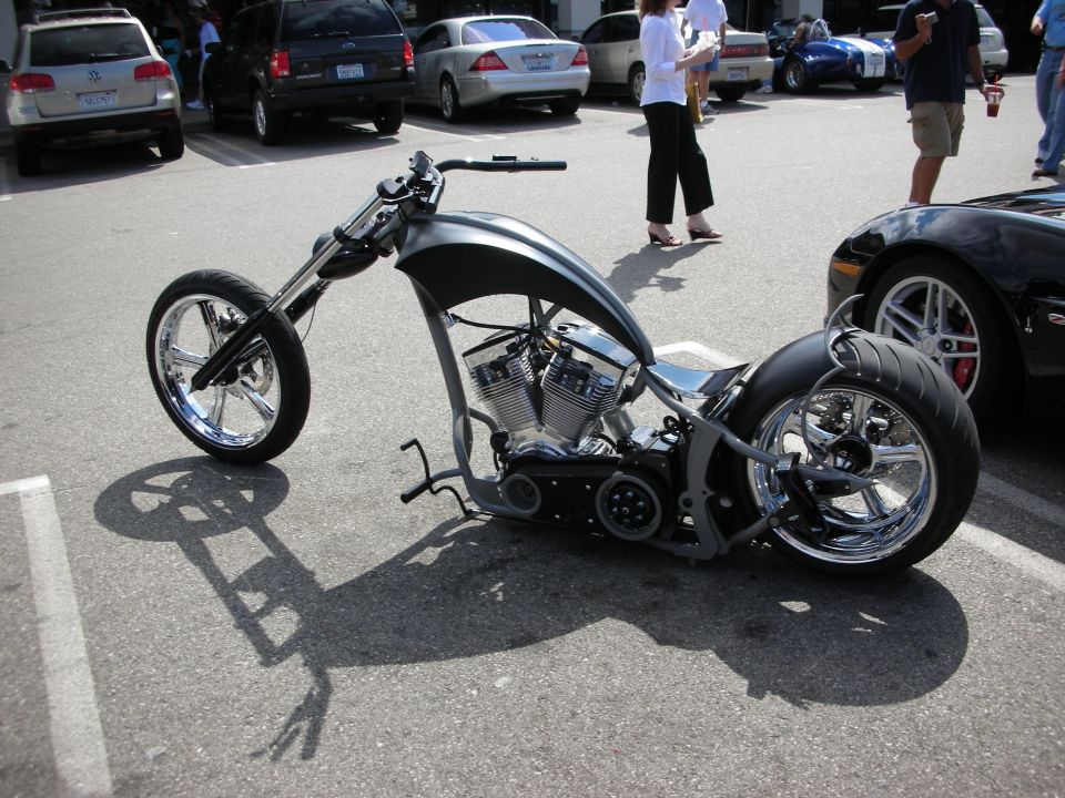 Silver custom chopper motorcycle with chrome wheels in a parking lot