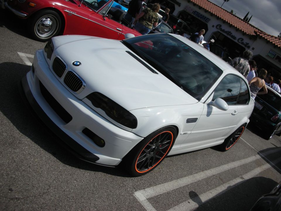 White BMW M3 coupe with black wheels and carbon hood at a car show