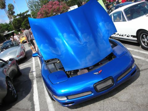 1998 Ford Crown Victoria - blue Chevrolet Corvette with its hood raised, displaying the engine bay and crossed-flags badge at an outdoor show.
