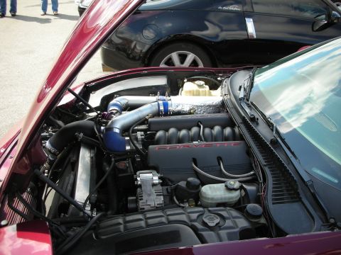 1998 Ford Crown Victoria - maroon Corvette's engine bay showing blue intake piping over the V8 with red CORVETTE script on the engine covers.