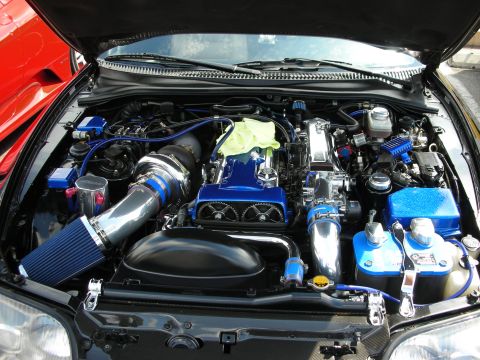 1998 Ford Crown Victoria - heavily modified engine bay with blue intake piping, a chrome turbo, blue valve covers and polished components.