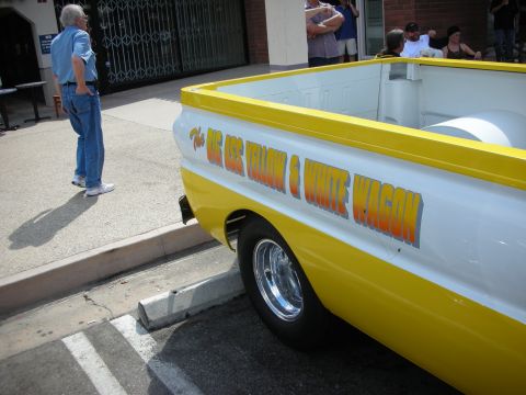 1998 Ford Crown Victoria - rear bed of a yellow-and-white pickup painted The Big Ass Yellow & White Wagon, with a man standing nearby on the street.