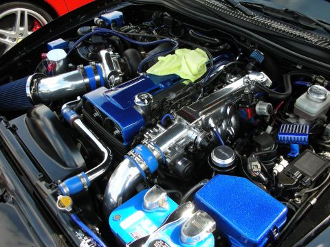 1998 Ford Crown Victoria - show-detailed engine bay featuring chrome turbochargers, blue intake piping and blue valve covers with a green rag draped over it.
