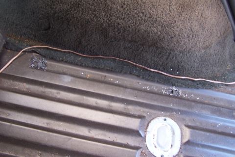1990 Ford Bronco - Close-up view of the interior cargo area floor, showing ribbed metal and carpeted trim.