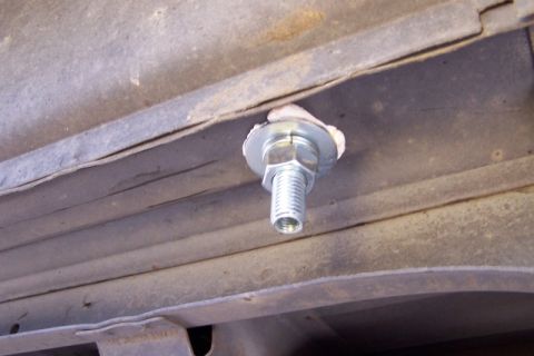 1990 Ford Bronco - A close-up view of a tie-down bolt attached to the underside of a vehicle, likely for securing cargo.