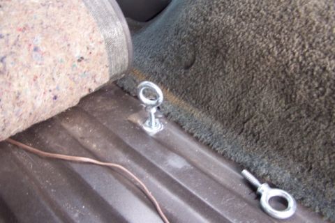 1990 Ford Bronco - Close-up of eye bolts for securing cargo in a vehicle's rear compartment.