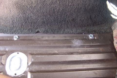 1990 Ford Bronco - The interior floor of a vehicle shows two bolts and a circular metal plate, likely for tie-down points.
