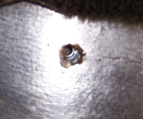 1990 Ford Bronco - A close-up view of a metal tie-down anchor point, showing a bolt within the hole.
