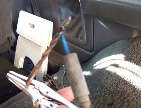 1990 Ford Bronco - A drill bit is heated by a torch inside a vehicle's interior, held by vice grips.