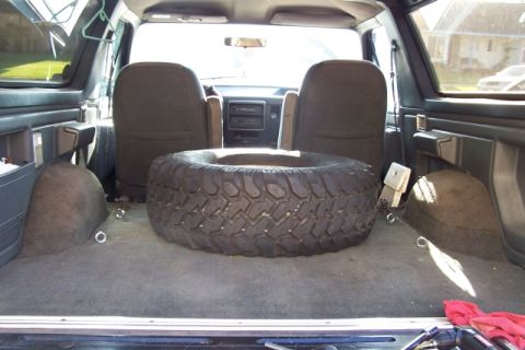 1990 Ford Bronco - The interior of a 1990 Ford Bronco shows a spare tire and tie-down points in the cargo area.
