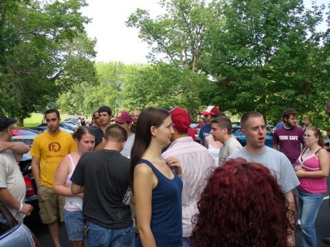 1991 Ford Probe - A crowd of people are gathered around several parked cars in an outdoor setting.