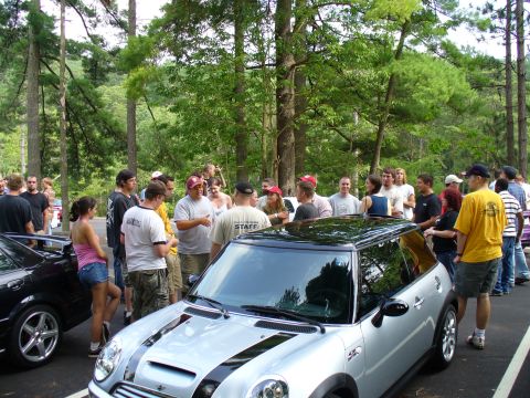 1991 Ford Probe - People gather around a silver Mini Cooper during an outdoor event.