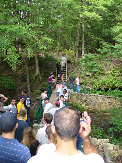 1991 Ford Probe - A group of people are seen on a bridge and stairs surrounded by trees, with a stream visible below.