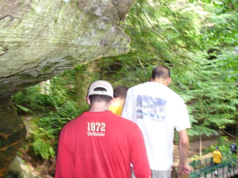 1991 Ford Probe - People walk through a lush green forest with large rock formations overhead.