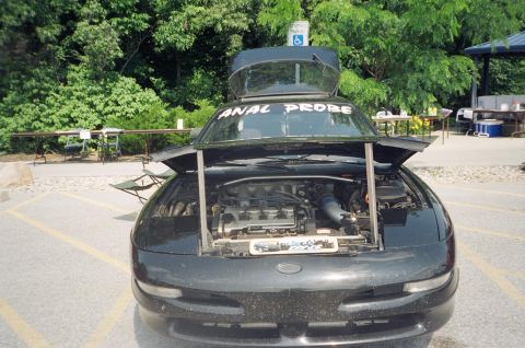 1995 Ford Probe - A black car is shown with its hood open, revealing the engine. Text on the windshield reads "ANAL PROBE".