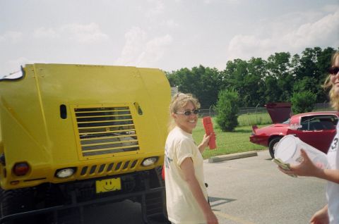 1995 Ford Probe - A yellow vehicle with a smiley face license plate is parked next to a red car at an outdoor event.