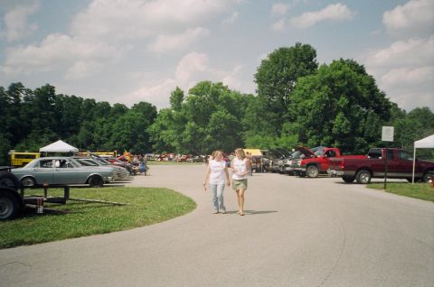 1995 Ford Probe - An outdoor gathering features numerous vehicles parked in rows under a partly cloudy sky.