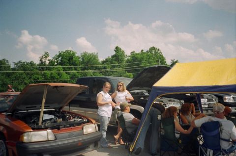1995 Ford Probe - Several vehicles and people are gathered at an outdoor event, with one car's hood open.
