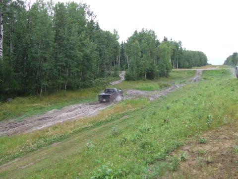 1988 Ford Bronco - Ford pickup truck navigating a muddy track through a wooded area.