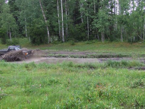 1988 Ford Bronco - Pickup truck navigating a muddy obstacle course in a wooded area.