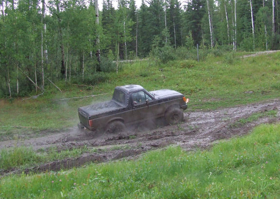 Ford Bronco II stuck in mud, kicking up dust