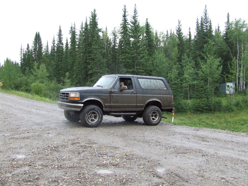 Dark green SUV with aftermarket wheels on a gravel road