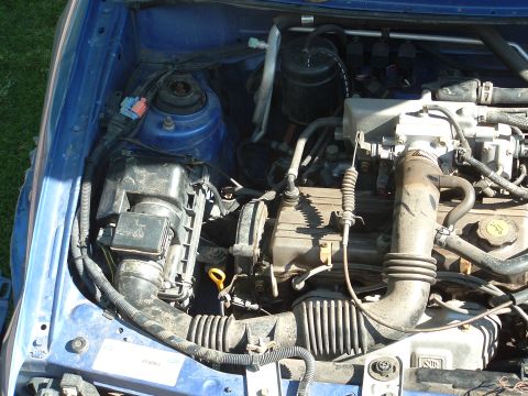 1995 Ford Aspire - Another shot of the dirty engine compartment, passenger side.
