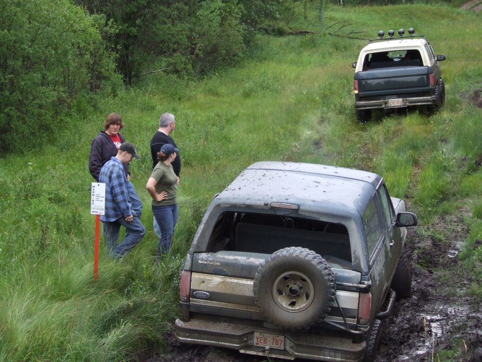 Dark gray Ford Bronco with a spare tire on the rear, stuck in mud
