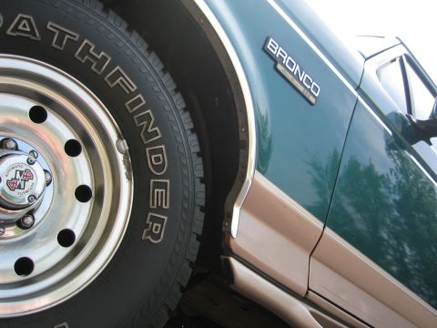 1996 Ford Bronco - A close-up view of a green Ford Bronco's fender and tire.