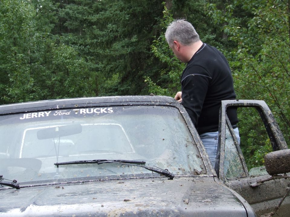 1988 Ford Bronco with 'JERRY Ford TRUCKS' sticker on windshield, man in black shirt leaning on roof