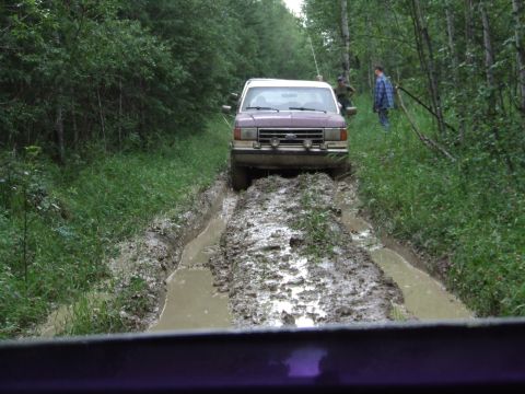 1988 Ford Bronco - Ford Bronco driving through a muddy, wooded area.