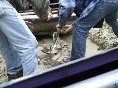 1988 Ford Bronco - People are trying to free a vehicle stuck in the mud with a strap.