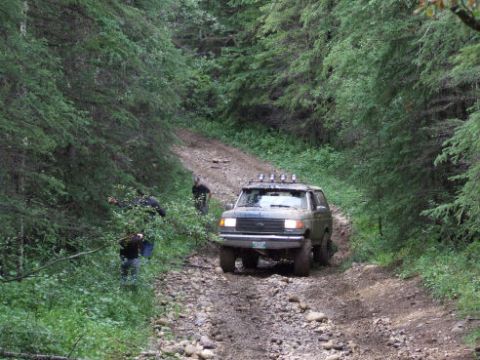 1988 Ford Bronco - A 1988 Ford Bronco navigates a rough, forested trail.