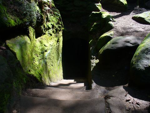 1991 Ford Probe - A path winds through moss-covered rocks towards a dark, cave-like entrance.