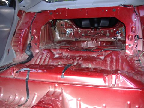 1998 Ford Taurus - The interior of a car shows exposed red metal flooring and wiring, suggesting a stripped-down or custom build.