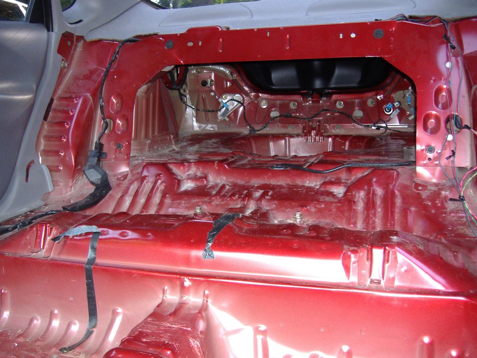 Interior of a car with red painted metal floor and exposed wiring