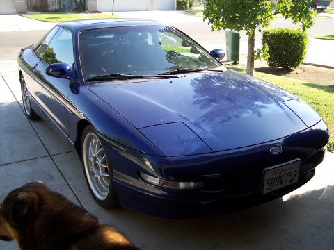 1995 Ford Probe - A blue 1995 Ford Probe is parked in a driveway, pop-up headlights and aftermarket wheels.