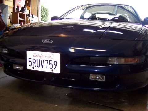1995 Ford Probe - A dark blue Ford Probe is parked in a garage, showing its front grille and headlights.