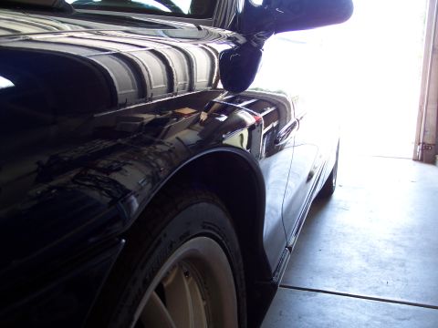 1995 Ford Probe - Close-up of a dark car's fender and side mirror, showing reflections in the glossy paint.