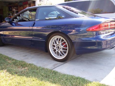 1995 Ford Probe - A blue 1995 Ford Probe GT is parked in a driveway, showing its distinctive body style and aftermarket wheels.