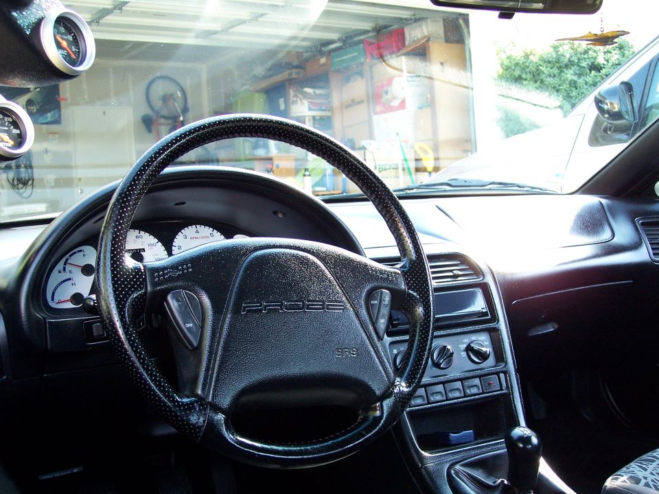 car interior, steering wheel with 'PROBE' text, dashboard, and two gauges on the A-pillar