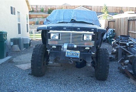 1986 Ford Bronco - This modified Ford truck sits in a driveway, its front end partially covered by a tarp.