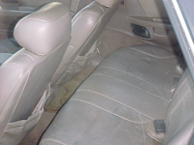Back seat and interior of a car. Shows worn leather seats and door panel