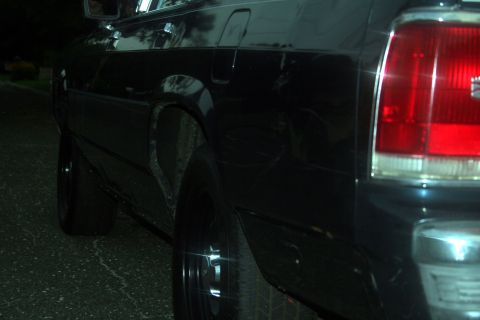 1989 Ford Crown Victoria LTD - A close-up view of the rear side of a black sedan, showing the taillight and wheel well.