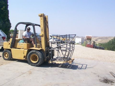 1978 Ford Bronco - A forklift transports a metal frame outdoors on a sunny day.