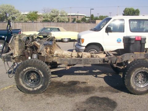 1978 Ford Bronco - The frame of a vehicle is shown with its engine and drivetrain components disassembled, parked outdoors.