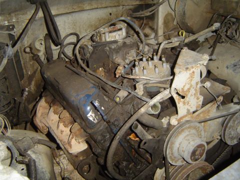 1972 Ford F-100 - The engine bay of a 1972 Ford F-100 shows a V8 engine covered in grime and dust.